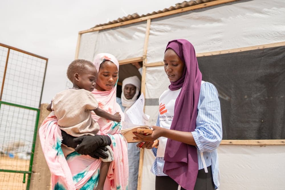 Doctors Without Borders/Médecins Sans Frontières staffer explaining services to refugees from Sudan